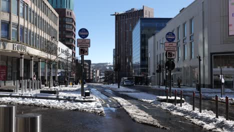 Sunny,-snowy-city-centre-street-with-cars-and-people,-Sheffield,-wide-angle