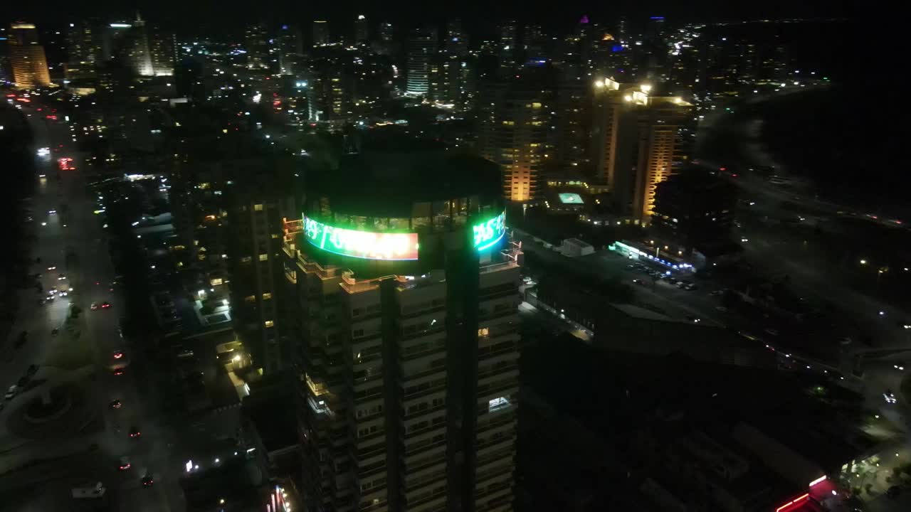 Luminous billboard illuminating Punta del este uruguay modern skyscraper skyline, casting vibrant led lights across nighttime urban landscape near coastline