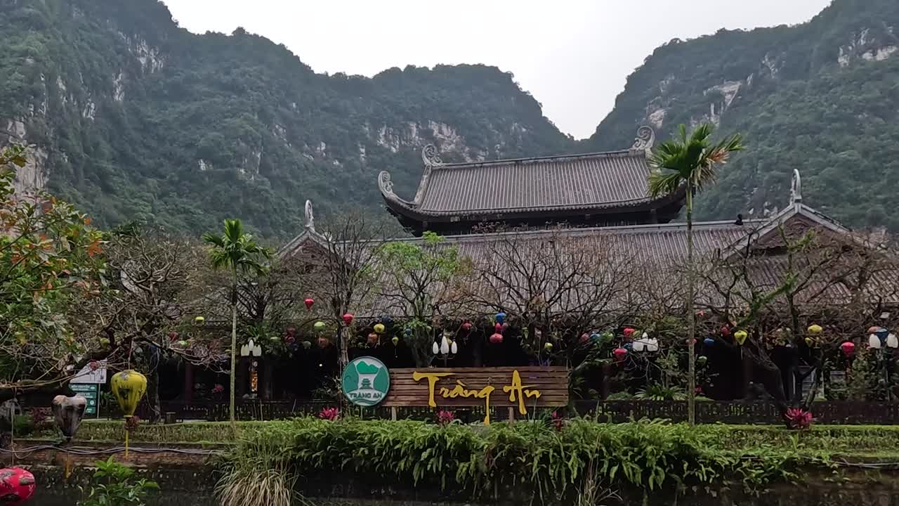 A scenic view of a traditional pavilion surrounded by lush greenery and mountains in the background.