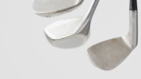 Close-up-of-golf-clubs-on-white-background,-copy-space,-slow-motion