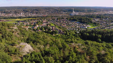 scenic aerial drone view of swedish mountain hill green forest with residential suburb in background, east of gothenburg, sweden, day, forward