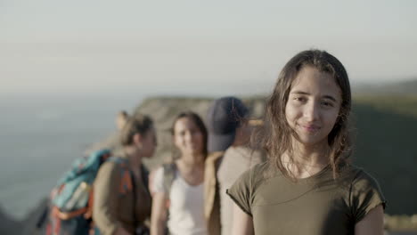 una senderista sonriente mirando a la cámara mientras su familia se queda atrás en un fondo borroso