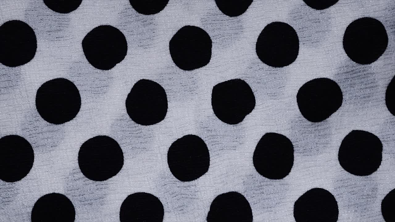 Spotted fabric cloth close up shot. Black dots on white background, Monochrome pattern.