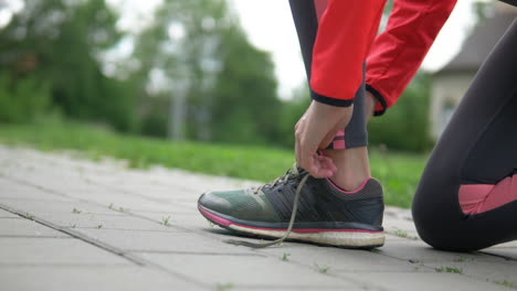 low to ground shot, woman in activewear tying shoelace preparing to run in park