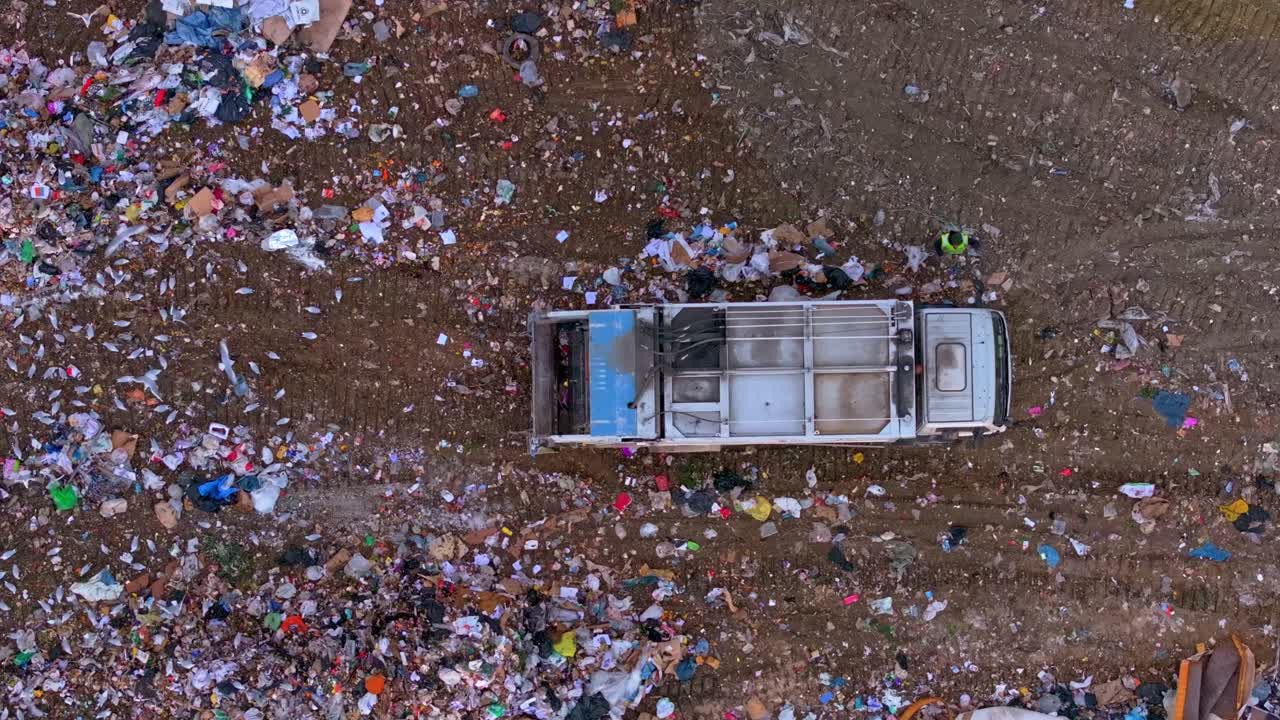 Ripresa aerea di una vasta area di rifiuti con macchinari pesanti che rimuovono i detriti