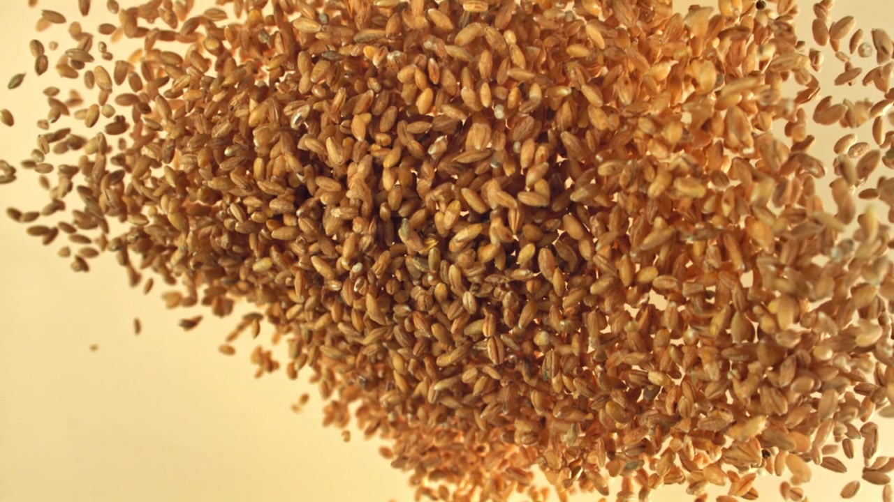Primo piano di chicchi di grano che cadono e si accumulano.