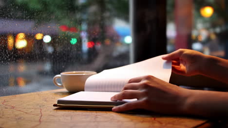 person reading a book or notebook in a cozy cafe on a rainy day