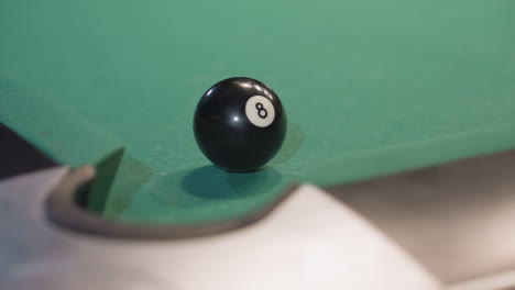 black billiard ball rolling on green pool table as white cue ball strikes it toward pocket. close-up captures precision, motion, and dynamics of game, highlighting crucial moment of shot execution