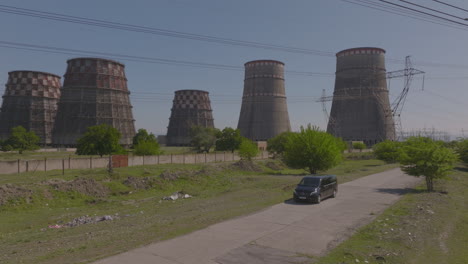 Static-aerial-shot-of-a-vehicle-sitting-outside-a-power-plant-with-chimney-stacks