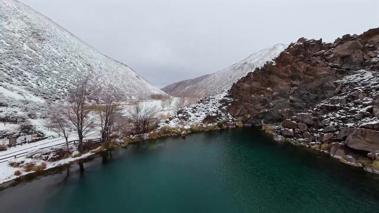 Mendoza'daki Laguna de la Nina Encantada'nın yanındaki karla kaplı patika, patika boyunca dinamik havadan FPV süzülüşü.