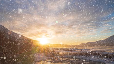 beautiful winter landscape of mountain lake at colorful sunrise. snowflakes falling in slow motion. winter background.