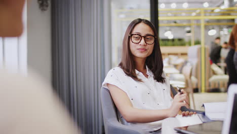 joven mujer asiática creativa hablando con su colega en una sala de reuniones, sobre la vista del hombro