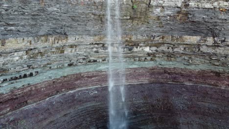 spectacular scenic view of famous devil’s punchbowl, rock formation with waterfall pouring down to the bottom located at hamilton, ontario canada, slow aerial pedestal down shot