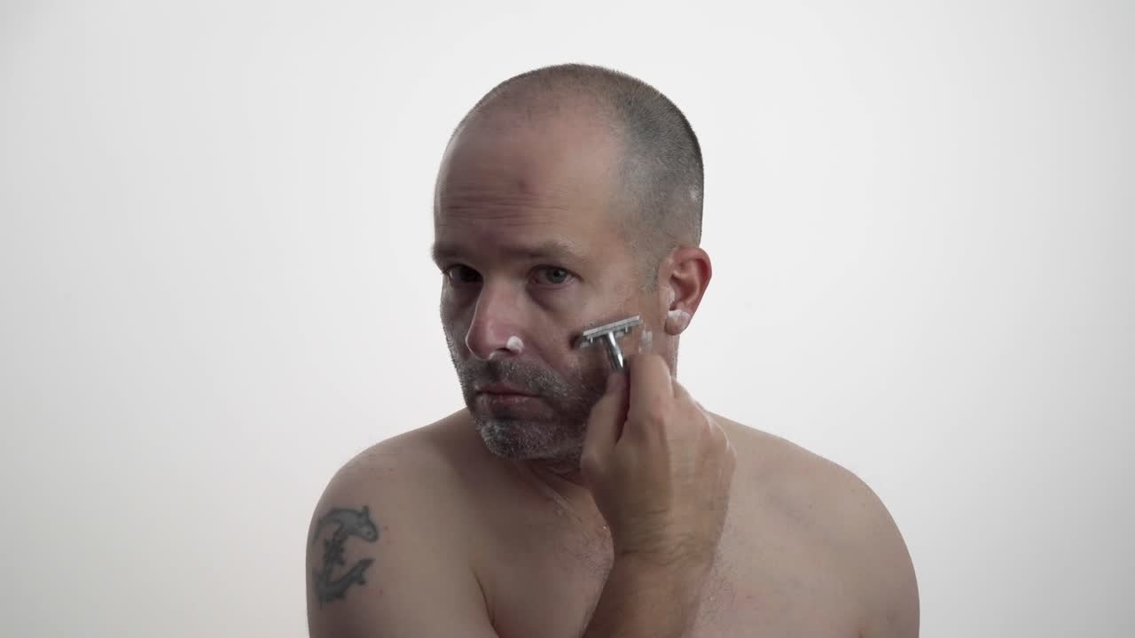 Man shaving his face while facing camera in 60fps UHD.