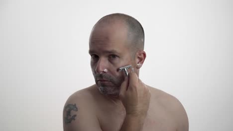 man shaving his face while facing camera in 60fps uhd.