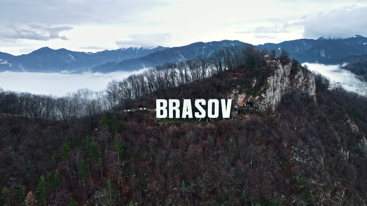 Brasov sign on the top of the hill near the city, bare trees, tourists, low clouds, Romania