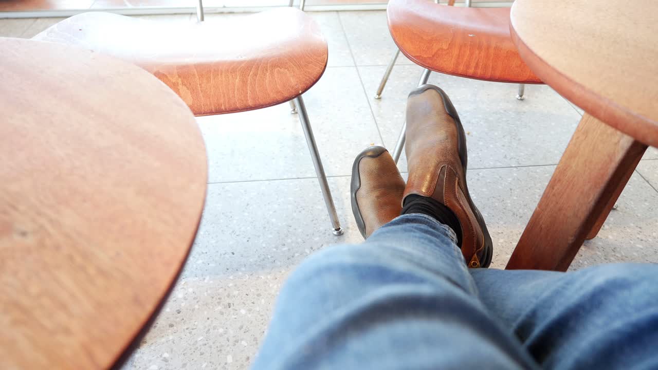 Persona seduta in un bar con gambe e stivali