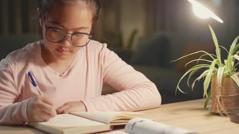 homeschooling, asian girl writing while sitting on table house night