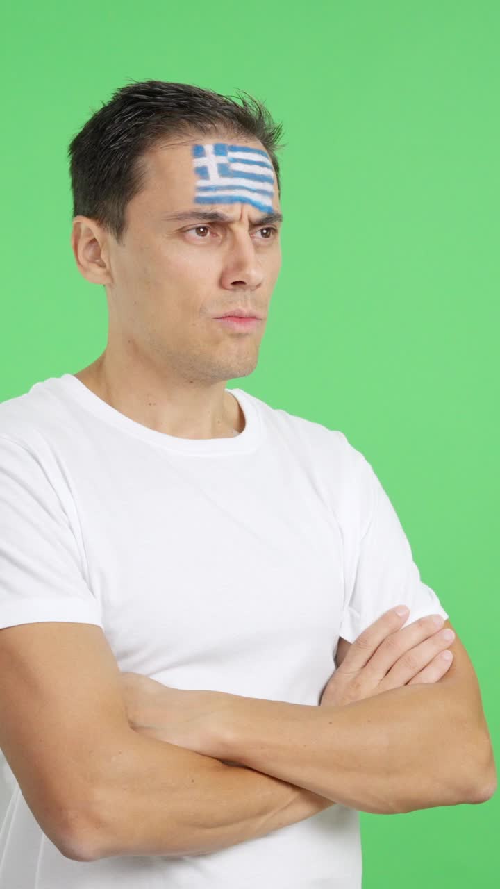 Man with greek flag painted looking away with serious expression