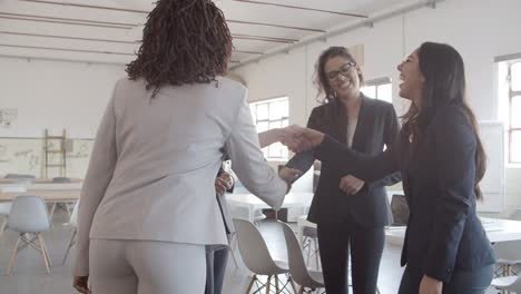 mujeres de negocios felices estrechando la mano en la oficina