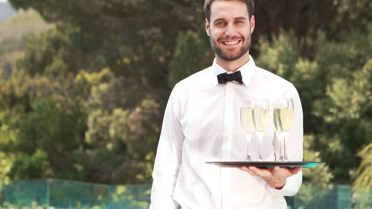 camarero sonriente sosteniendo copas de champán