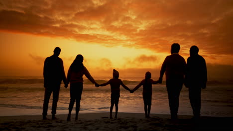 playa, puesta de sol y gran familia tomados de la mano