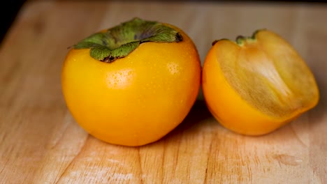 two persimmons displayed on a wooden surface
