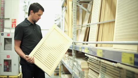 man shopping for wood panels at a home improvement store