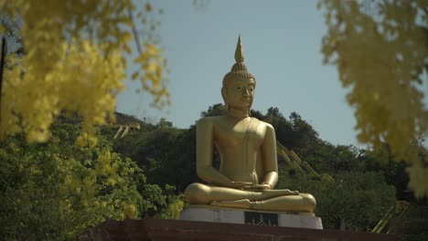 una estatua dorada de buda sentada rodeada de flores amarillas