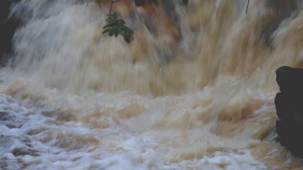 Fast flowing peat coloured water in Welsh river after heavy rain