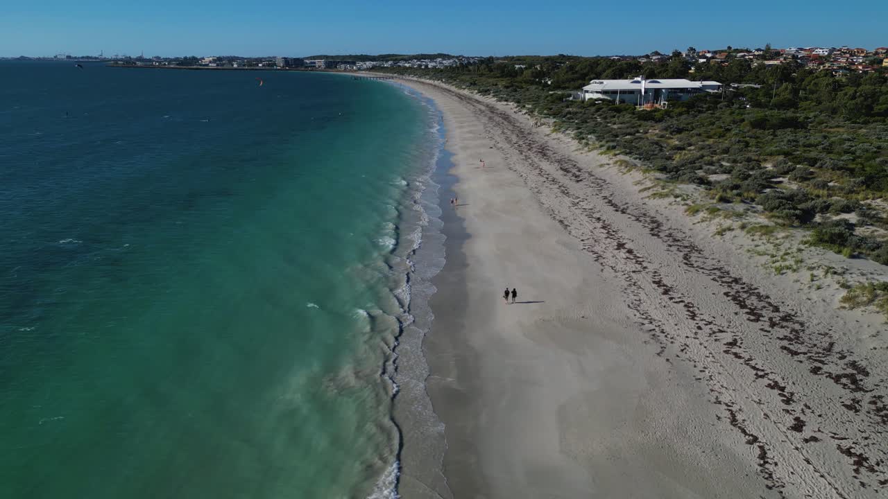 drone aéreo en movimiento hacia adelante disparado sobre algunos turistas caminando a lo largo de la costa de coogee beach en un día de verano en perth, australia occidental