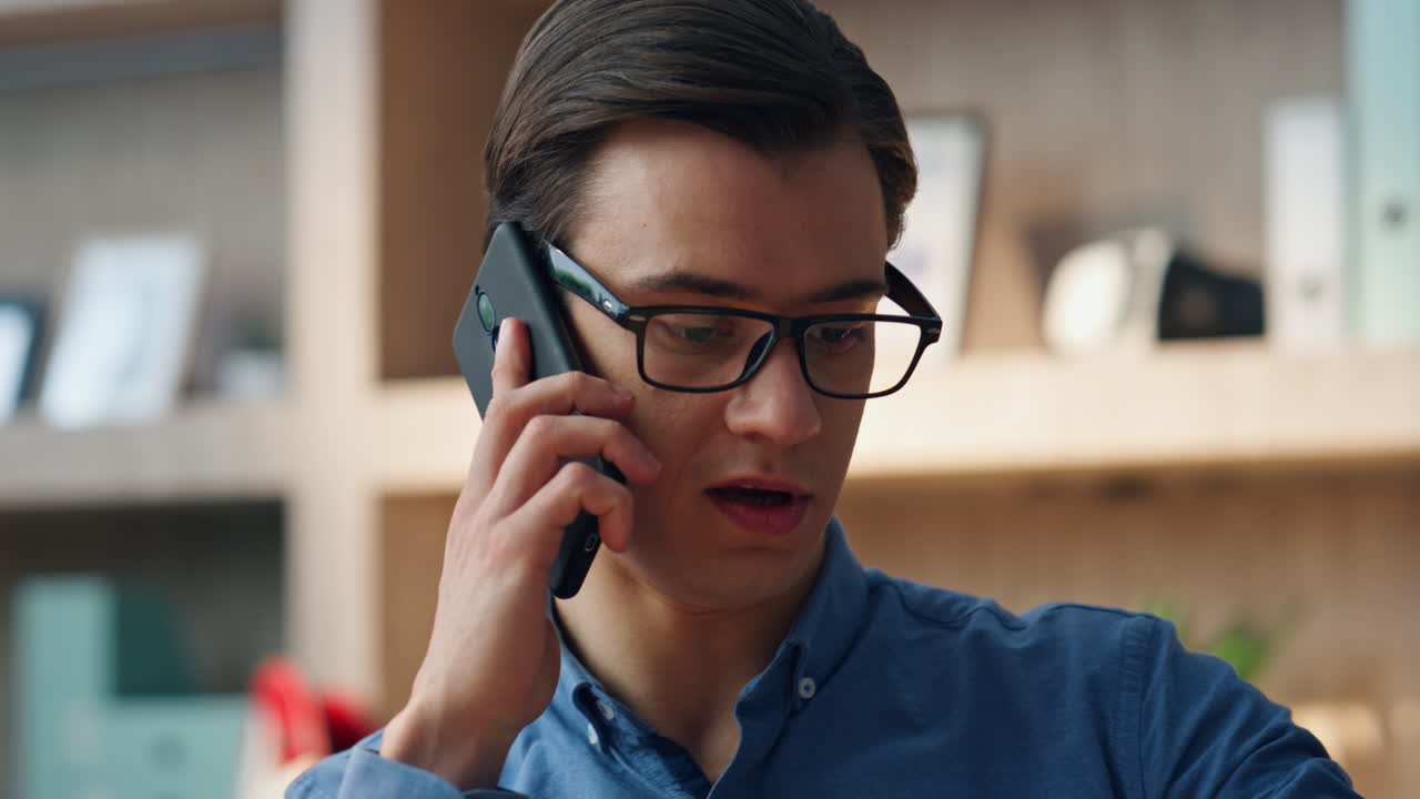편안한 디자이너가 사무실에서 스마트 폰을 집어 들고 심각한 남자가 대답합니다.