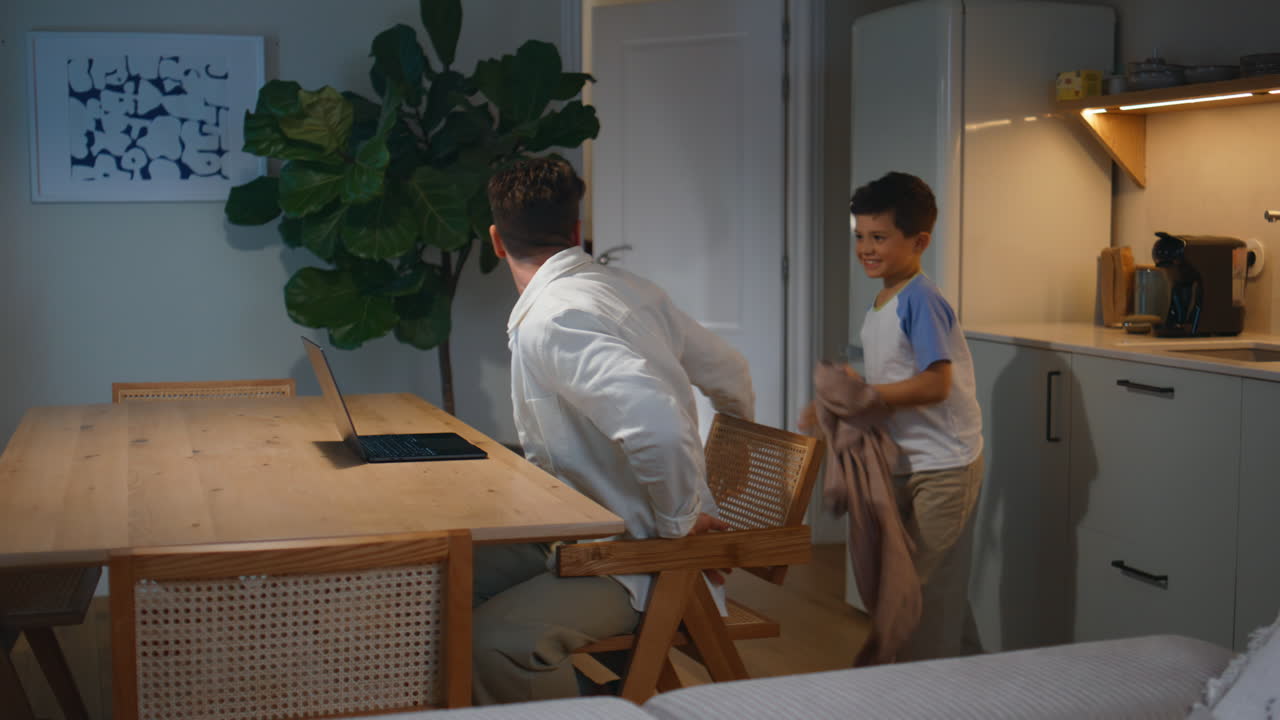 Naughty kid disturbing father at evening apartment. Angry man arguing on child