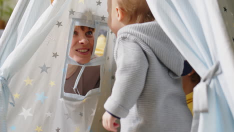 mother playing with kids in teepee