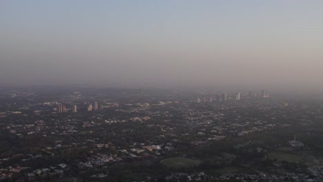 aerial shot of islamabad’s skyline and faisal mosque under evening haze. islamabad, pakistan