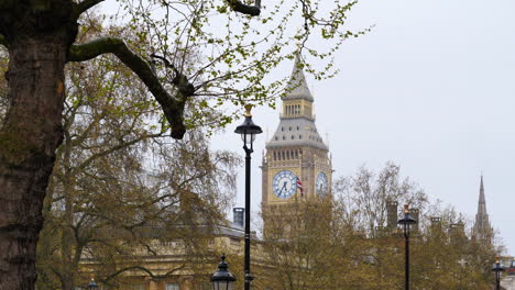 bella scena di big ben vista attraverso gli alberi, bandiera britannica sventolante
