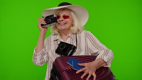 senior woman tourist photographer taking photos on retro camera and smiling on chroma key background