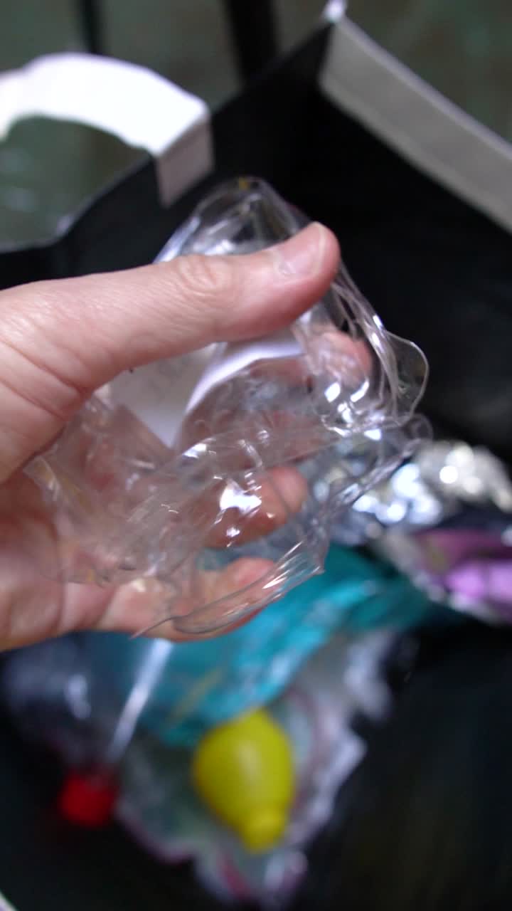 A close-up of a hand squeezing plastic stuff into a recycling bag, promoting a green initiative and responsible waste management at home