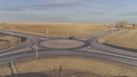 a modern roundabout in the middle of nowhere, cars navigate a circle