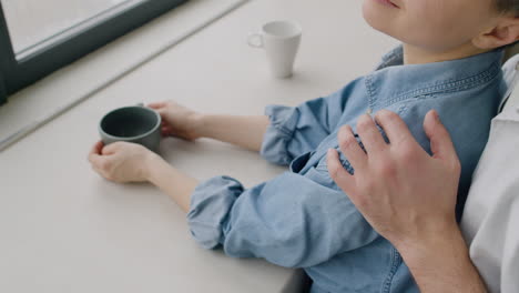 close up of an unrecognizable man tenderly hugging his smiling girlfriend from the back at home in the morning