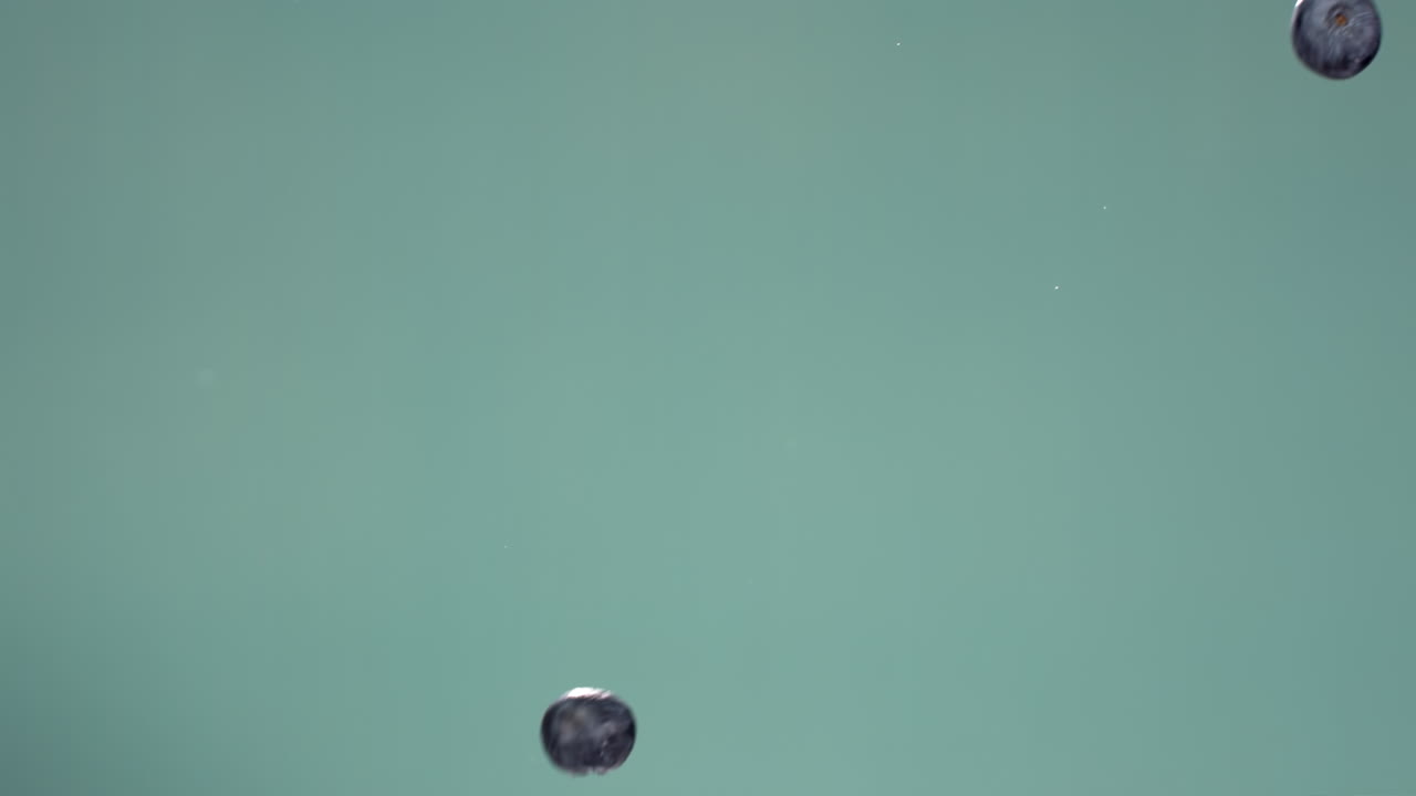 푸른 배경에 대비하여 공중에서 날아다니는 블루베리의 슈퍼 슬로 모션, 고속 카메라로 촬영, 420fps