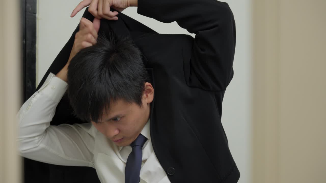 아시아인 남자는 거울 앞에 슈트 재을 입고 자신감을 느끼면서 미소 짓습니다.