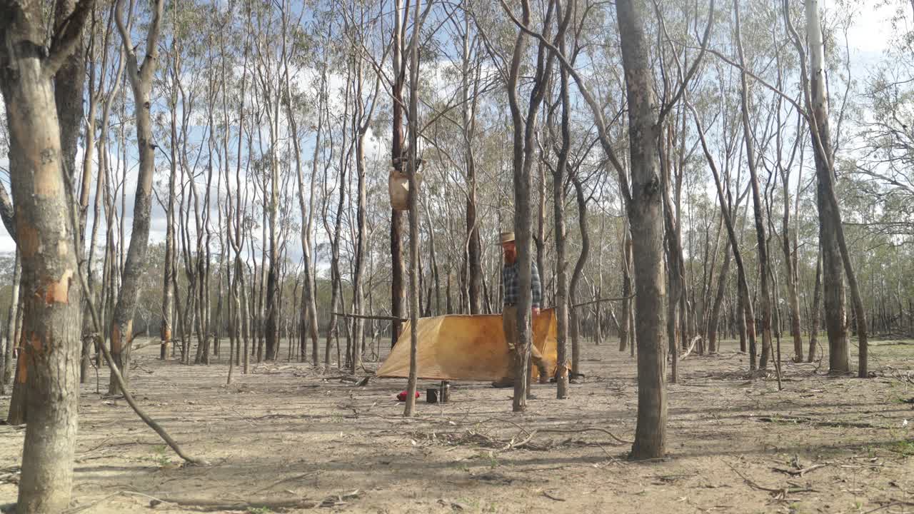 A traditional bushman camped in a historical style tent in the Australian outback.