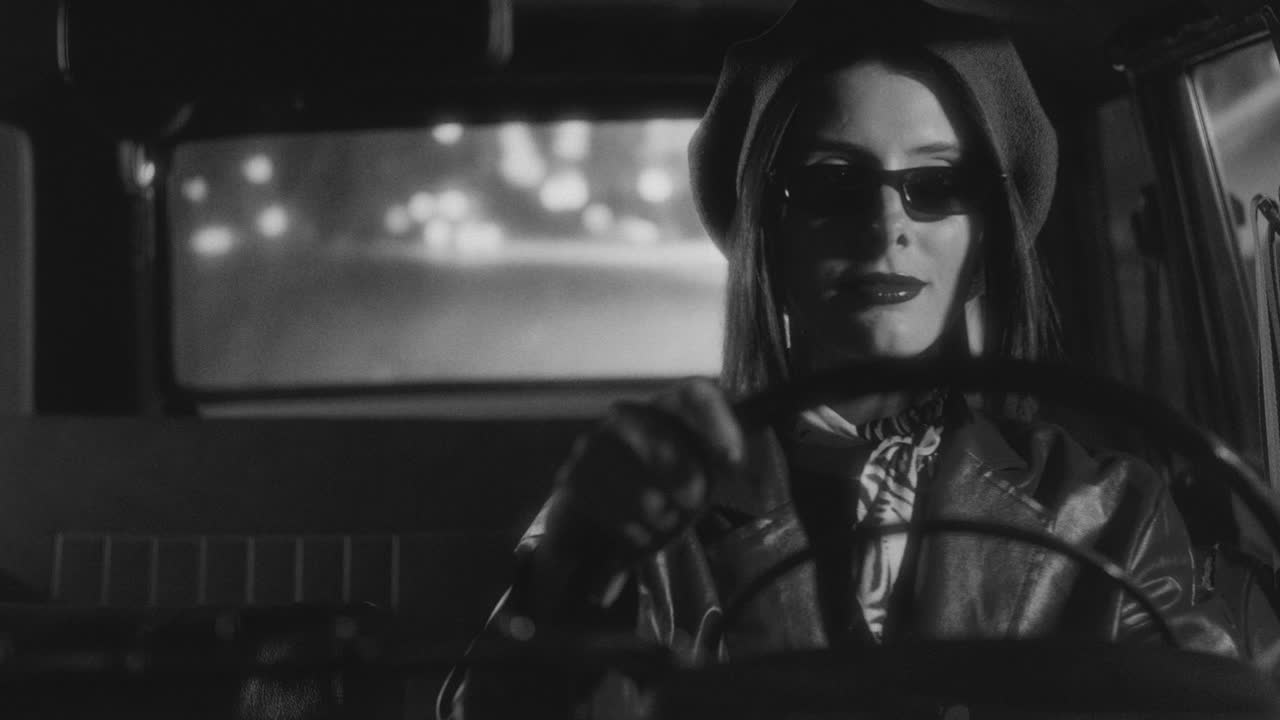 Black and White Portrait of Confident Woman Driving Classic Car at Night