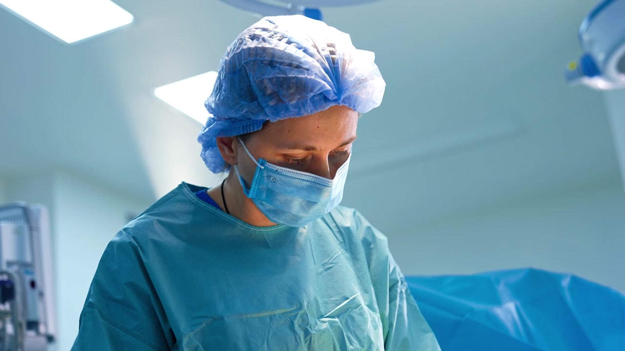 Medico donna caucasica in uniforme per l'intervento. Ritratto di una chirurga che lavora in sala operatoria.