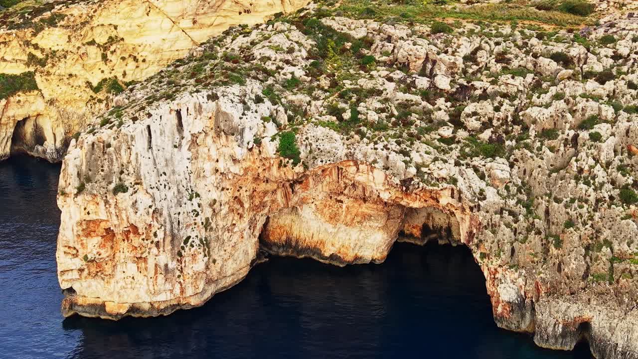 Malta's rocky coastline and natural arch during sunny weather