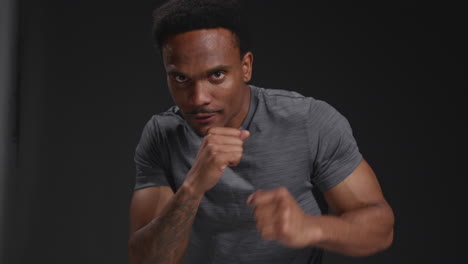 close up studio portrait of male boxer training in gym sparring towards camera and warming up preparing for fight against black background 1