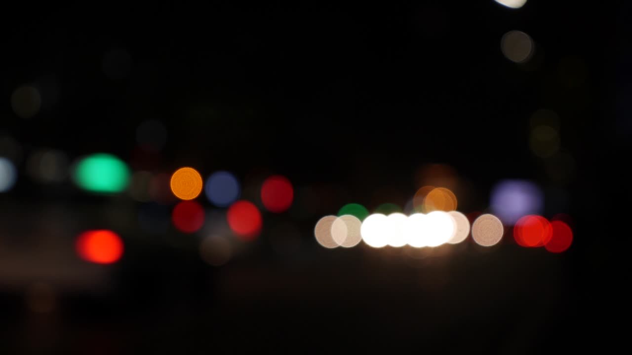 hermoso bokeh brillante en el fondo oscuro borroso por la noche. el redondo bokeh colorido brilla de las luces de los coches en la calle de la ciudad. fuera de foco con borroso. luces de la ciudad sin enfoque. bokeh de tráfico. concepto abstracto