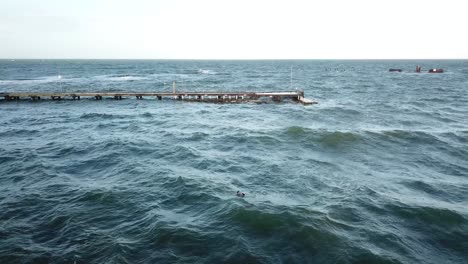 Drone-aerial-over-ocean-Melbourne-wavy-windy-cloudy-man-swimming-in-winter