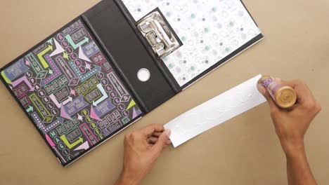 applying glue on piece of paper to place in scrapbook with cool design
